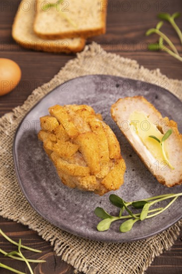 Chicken Schnitzel on gray plate with microgreen on brown wooden background and linen textile. side view, close up, selective focus
