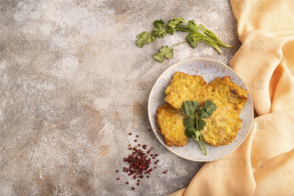 Fried crispy Chicken pancakes on brown concrete background and orange linen textile. top view, flat lay, copy space