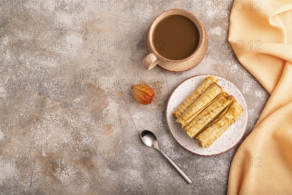 Waffles with caramel on brown concrete background and orange linen textile, cup of coffee, top view, flat lay, copy space