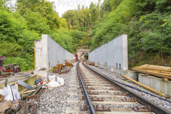 Eisenbahnschienen führen zu einem Tunnel, umgeben von Baustellenmaterialien und Wald, Bau der Hermann Hessenahn, Calw, Schwarzwald, Deutschland