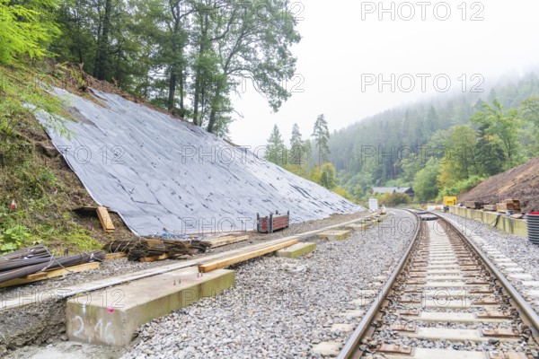 Bahnstrecke mit Gleisen entlang eines Hangs, gesichert durch Planen im Wald, Bau der Hermann Hessenahn, Calw, Schwarzwald, Deutschland