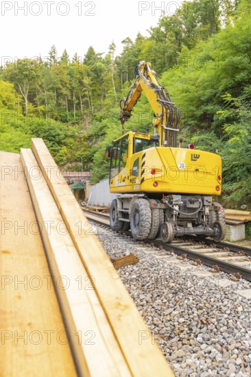 Gelbes Baufahrzeug mit Kran auf Schienen in waldreicher Umgebung, Bau der Hermann Hessenahn, Calw, Schwarzwald, Deutschland