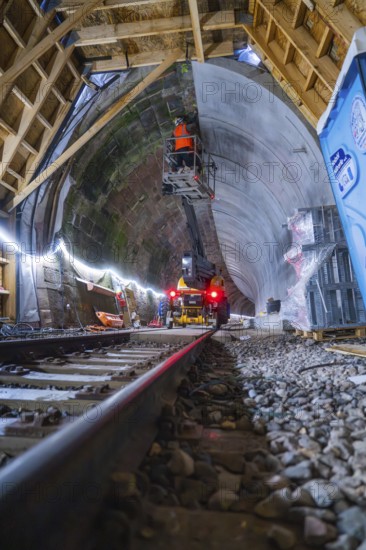 Tunnelbau mit Schienen, Maschinen, beleuchteter Atmosphäre und einem Bauarbeiter in Aktion, Bau der Hermann Hessenahn, Calw, Schwarzwald, Deutschland