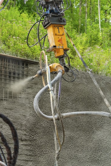 Nahaufnahme einer Maschine, die Beton auf eine Struktur sprüht, umgeben von grüner Vegetation, Bau der Hermann Hessenahn, Calw, Schwarzwald, Deutschland