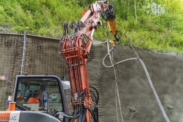 Maschine sprüht Beton an einer Wand entlang eines bewachsenen Bauplatzes, Bau der Hermann Hessenahn, Calw, Schwarzwald, Deutschland