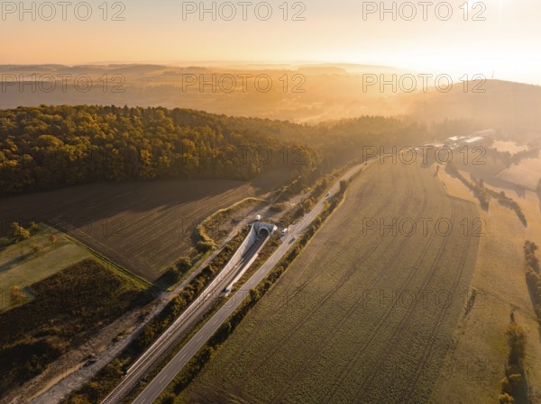 Panoramablick über eine hügelige Landschaft mit Feldern und einer Straße im goldenen Sonnenlicht, Neubautunnel der Hermann Hessebahn, Calw, Schwarzwald, Deutschland