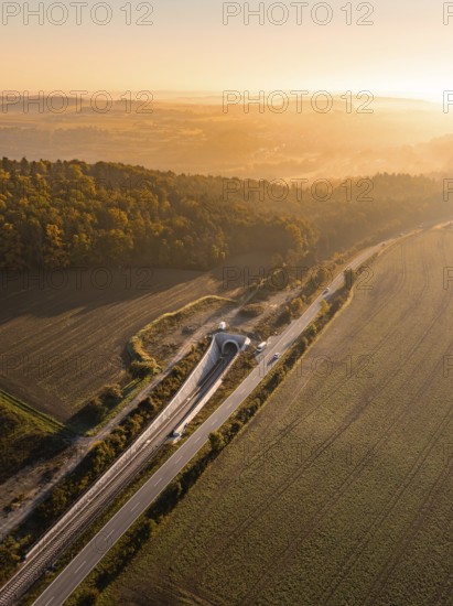Luftaufnahme einer Landschaft mit Feldern, Hügeln, einer Straße und einer Eisenbahnlinie bei Dämmerung, Neubautunnel der Hermann Hessebahn, Calw, Schwarzwald, Deutschland