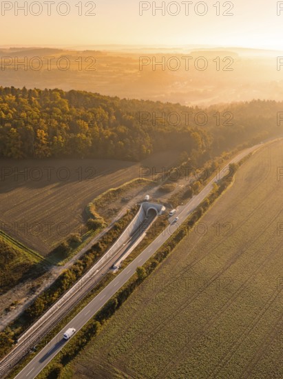 Dämmerungsaufnahme einer ländlichen Landschaft mit Eisenbahn, Straße und Felder, flankiert von einem Wald, Neubautunnel der Hermann Hessebahn, Calw, Schwarzwald, Deutschland