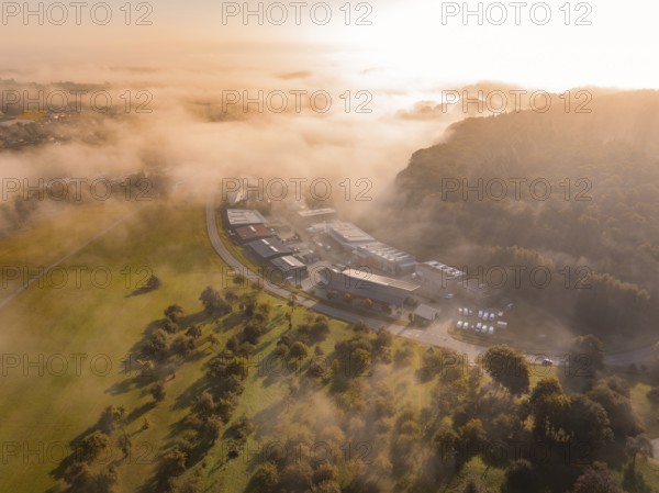 Nebel und Morgensonne schaffen eine atmosphärische Landschaft über Industriegebäuden, Gechingen, Heckengäu, Landkreis Calw, Deutschland