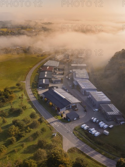 Industriegebäude neben einer Straße in nebliger Morgenstimmung aufgenommen, Gechingen, Heckengäu, Landkreis Calw, Deutschland