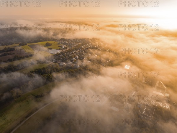 Luftaufnahme eines Dorfes im Nebel mit warmem Morgenlicht, die Landschaft wirkt weich, Gechingen, Heckengäu, Landkreis Calw, Deutschland