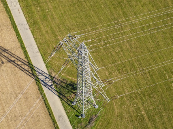 Hochspannungsmast steht auf einer Wiese, Schatten fällt über Felder im Sonnenlicht, Nagold, Schwarzwald, Deutschland