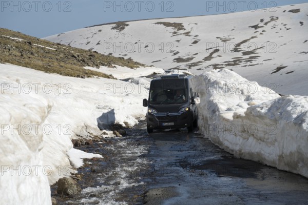 Van navigiert durch schmale, schneebedeckte Bergstraße bei Sonnenlicht, mit dem Camper zum Aragaz, Aragats, Aragac, Alagyaz, erloschener Schichtvulkan, 4090 m, Aragazotn, Schirak, Armenien