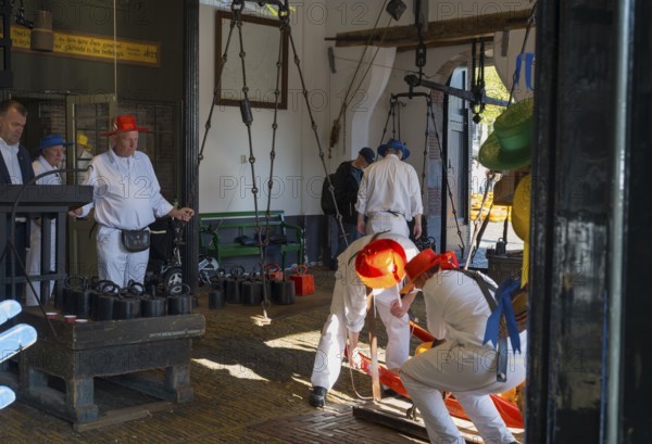 Männer in weiß mit roten Hüten bei der Arbeit auf einem Käsemarkt, ehemalige Stadtwaage, Käse wiegen, Käseträger, Käse, Käsemarkt, Alkmaar, Alkmar, Noord-Holland, Nordholland, Niederlande