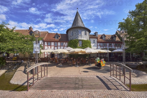 Fachwerkhäuser, Turm, Häuserzeile, Fußgängerbrücke, Holzbrücke, hölzern, Altstadt, historische Gebäude, Gehweg aus Klinker, Pflastersteine, Restaurant Zum Türmchen, Außenbereich einer Gastronomie mit Sonnenschirmen, Tischen und Stühlen, blauer Himmel, Cumuluswolken, Cirrostratuswolken, Platz am Untertor, Burggrabenstraße, Hofheim am Taunus, Main-Taunus-Kreis, Hessen, Deutschland