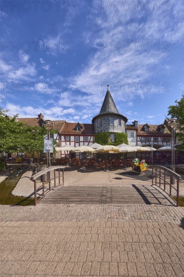 Fachwerkhäuser, Turm, Häuserzeile, Fußgängerbrücke, Holzbrücke, hölzern, Altstadt, historische Gebäude, Gehweg aus Klinker, Pflastersteine, Restaurant Zum Türmchen, Außenbereich einer Gastronomie mit Sonnenschirmen, Tischen und Stühlen, blauer Himmel, Cumuluswolken, Cirrostratuswolken, Platz am Untertor, Burggrabenstraße, Hofheim am Taunus, Main-Taunus-Kreis, Hessen, Deutschland