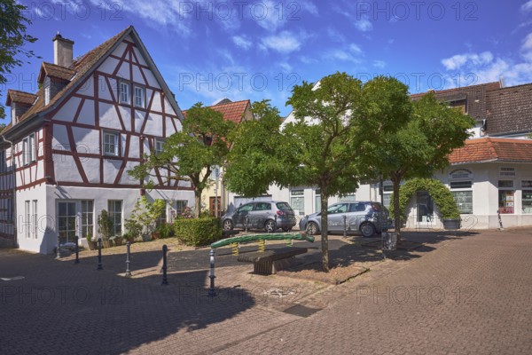 Platz, Straßen, Fachwerkhaus, allgemeine Architektur, Absperrpoller, Parkstreifen mit Fahrzeugen, Bäume, Sitzbänke, öffentlicher Mülleimer, blauer Himmel, Cumuluswolken, Kreuzung Bornplatz mit Kurhausstraße und Krebsgasse, Hofheim am Taunus, Main-Taunus-Kreis, Hessen, Deutschland