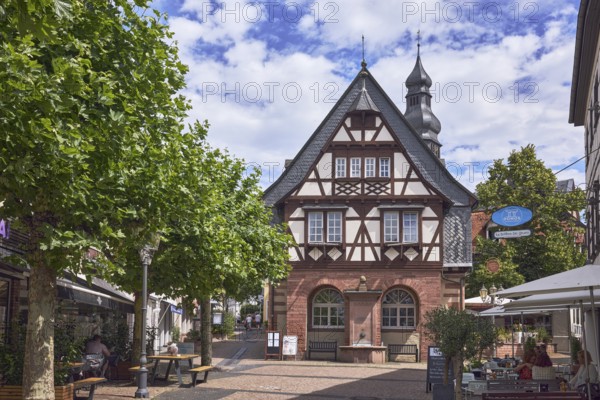 Historisches Rathaus, Altes Rathaus Café Hofheim am Taunus, Fußgängerzone, Fachwerkhaus, allgemeine Architektur, Außenbereich einer Gastronomie mit Sonnenschirmen, Nasenschild, Bäume, blauer Himmel, Altocumuluswolken, Cumuluswolken, Kreuzung Langgasse mit Hauptstraße, Hofheim am Taunus, Main-Taunus-Kreis, Hessen, Deutschland