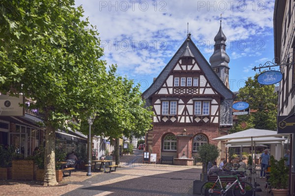 Historisches Rathaus, Altes Rathaus Café Hofheim am Taunus, Fußgängerzone, Fachwerkhaus, allgemeine Architektur, Außenbereich einer Gastronomie mit Sonnenschirmen, Nasenschild, Kirchturm der Pfarrkirche St. Peter und Paul, Bäume, blauer Himmel, Altocumuluswolken, Langgasse, Hauptstraße, Hofheim am Taunus, Main-Taunus-Kreis, Hessen, Deutschland