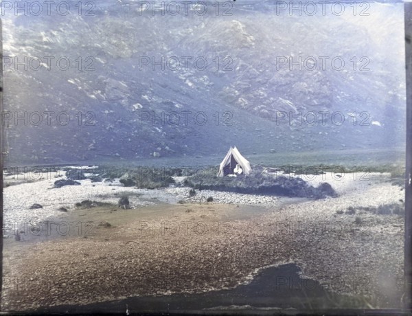 Tent camp on island in river of mountain valley, thought to be Cuillin mountains, Skye, Scotland, UK c 1900-1920 colourised image