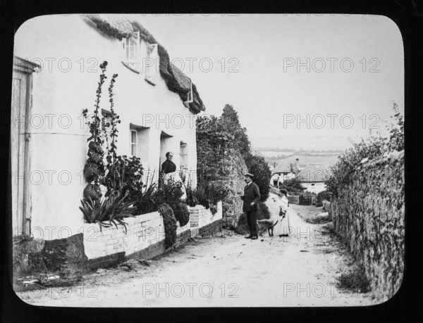Magic lantern slide c 1900-1910 of people in country lane of village with thatched cottages