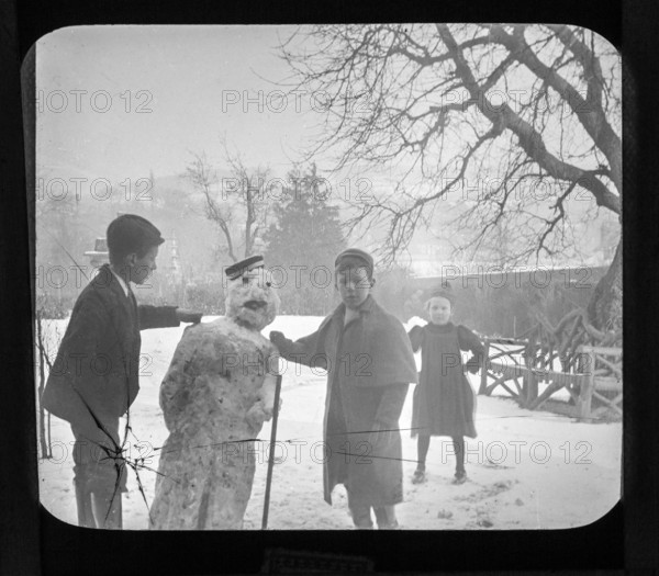 Magic lantern slide c 1900-1910 of children making a snowman in garden