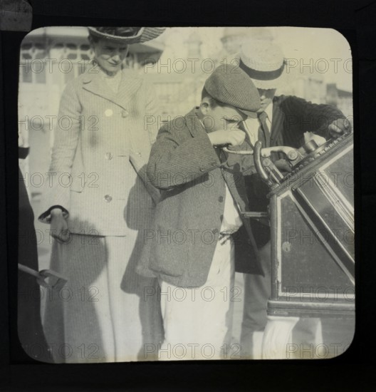 Magic lantern slide mother watching of two boys using a Roovers Metal Stamping Machine at the seaside, England, UK c 1900-1910
