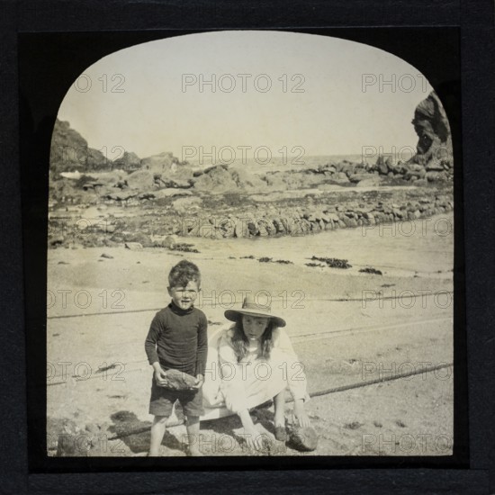 Magic lantern slide two children playing on a sandy beach circa 1900 location not known, presumed to be England, UK perhaps Cornwall