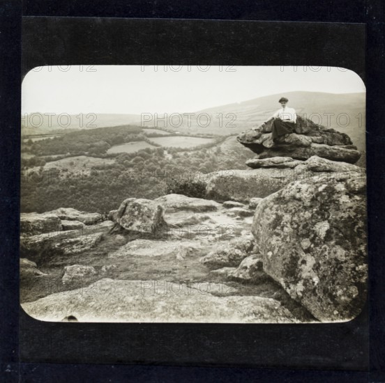 Magic lantern slide of woman sitting on mountain peak in countryside England, UK circa 1900 possibly Dartmoor