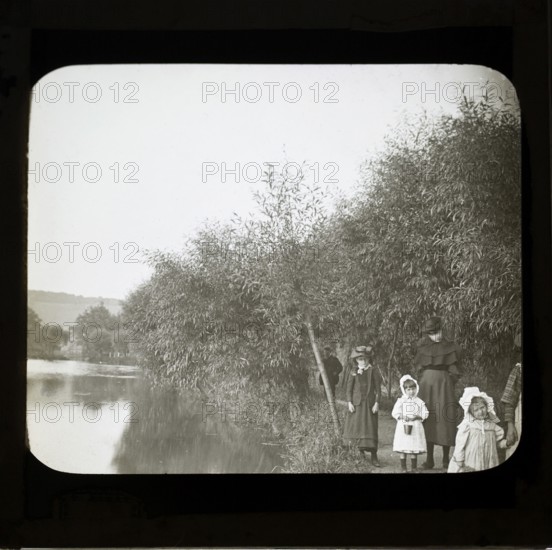 Magic lanterns slide of Edwardian children walking on a footpath next to a river, England, UK c 1900