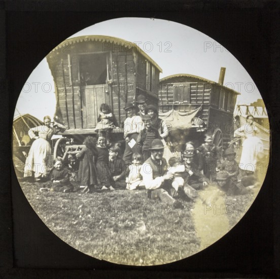 Magic lantern slide portrait of fairground travelling gypsy extended family and caravans, UK circa 1900