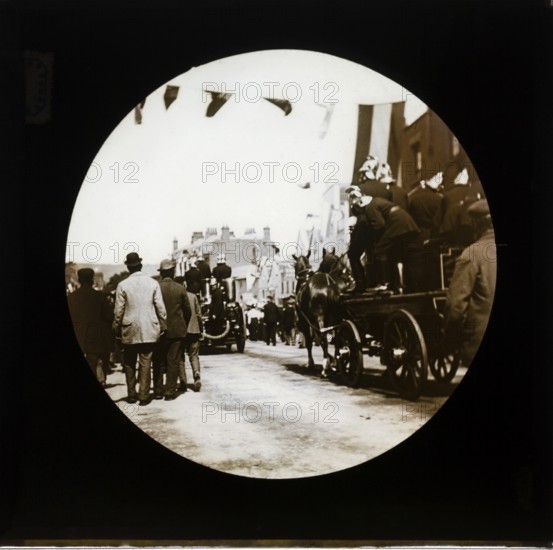 Horse drawn fire engines procession at a patriotic event with bunting flags across the street, possibly Edinburgh, Scotland, end of Boer War 1902