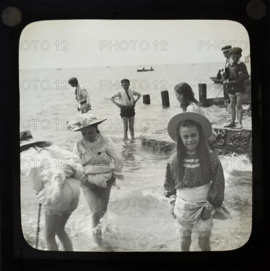 Magic lantern slide of children boys and girls paddling playing in the sea, UK circa 1900
