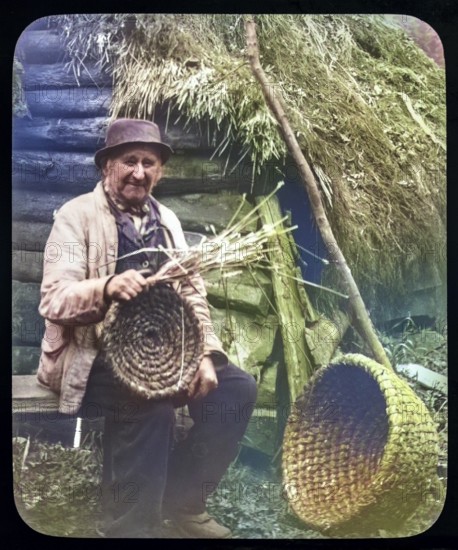 Portrait of elderly countryman weaving straw baskets in England, c 1890s-1900