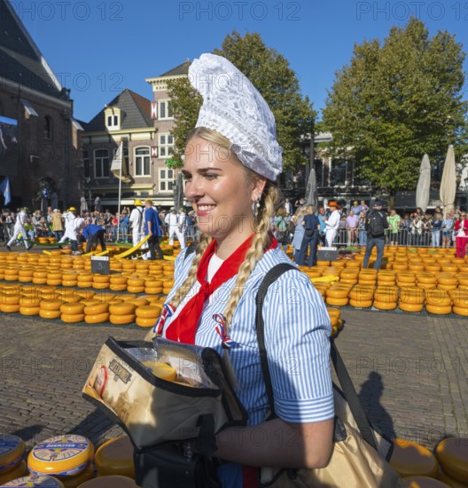 Smiling woman in traditional traditional costume carrying cheese at a busy market, cheese, cheese market, Alkmaar, Alkmar, Noord-Holland, Noord-Holland, Netherlands