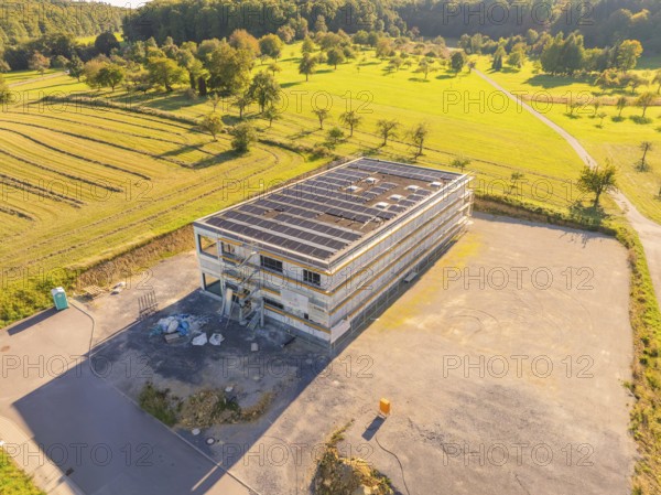 Building with solar panels, surrounded by landscape and fields, partly under construction, new building with green roof and PV system, Wiernsheim, Germany