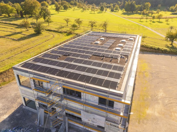 Building with solar panels and scaffolding in a green landscape, new building with green roof and PV system, Wiernsheim, Germany