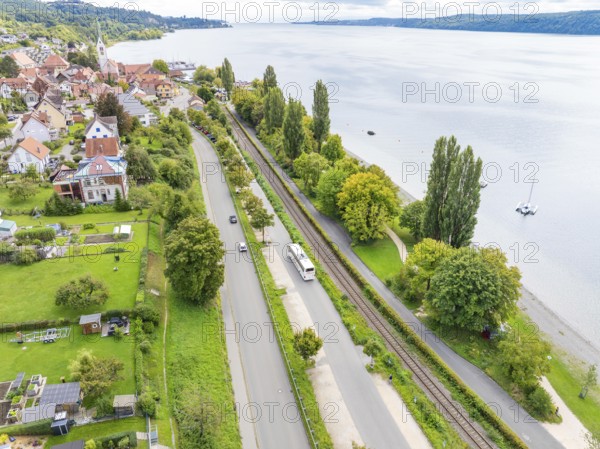 View of a town with road and railway tracks along a lake, surrounded by green areas, Lake Constance Germany