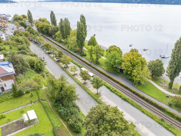 Bird's eye view of a road and railway track flanked by trees and a lake, Lake Constance Germany