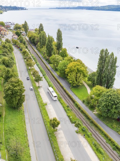 Aerial view of a road and railway line along a lake with trees and buildings, Lake Constance Germany
