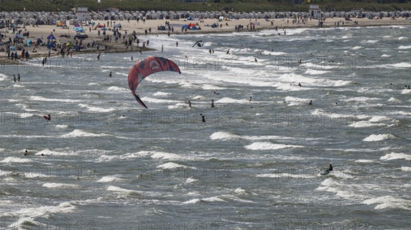 Kitesurfers and holidaymakers on the beach and in the sea, waves, beach chairs in the background, Warnemünde, Rostock, Mecklenburg-Vorpommern, Germany