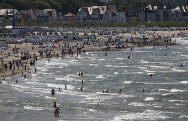 Holidaymakers on the beach and in the sea, waves, beach chairs in the background, Warnemünde, Rostock, Mecklenburg-Vorpommern, Germany
