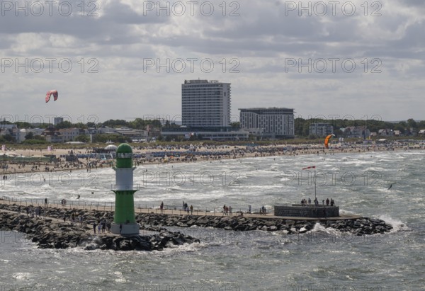 Green and white lighthouse, pier light Westmole in front of lively beach and hotels in the background, waves, Warnemünde, Rostock, Mecklenburg-Western Pomerania, Germany