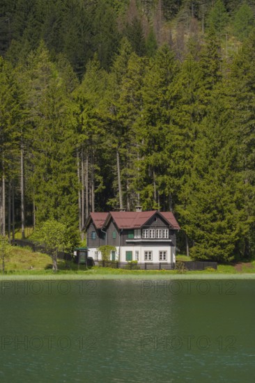 View over Lake Toblach to a house standing directly on the shore, Toblach, Höhlensteintal, South Tyrol, Italy