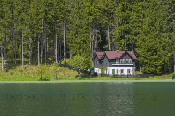 View over Lake Toblach to a house standing directly on the shore, Toblach, Höhlensteintal, South Tyrol, Italy
