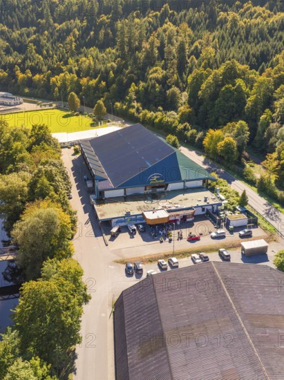Industrial building in the forest next to a road, large car park, shady areas, green surroundings, Polarion ice stadium, Bad Liebenzell, Black Forest, Germany