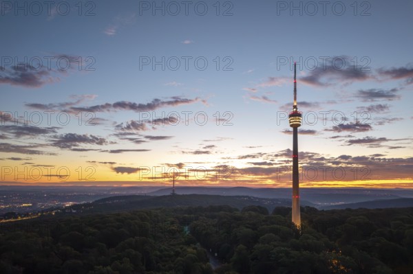 Illuminated television tower rises above forest in the morning red with clouds, Stuttgart-Degerloch, Baden-Württemberg, Germany