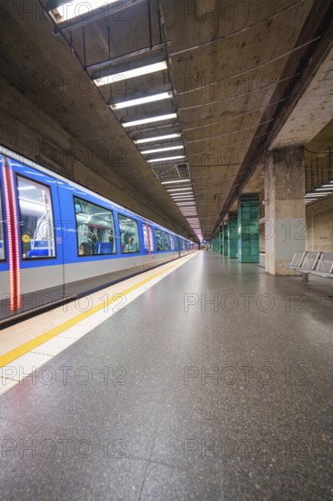 Modern underground station with illuminated train on an empty platform, Munich, Germany