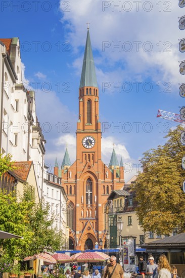 A busy urban centre is dominated by a tall church tower, Munich, Germany
