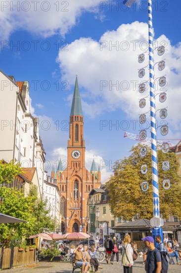 A lively city centre with a high church tower and a maypole, Munich, Germany
